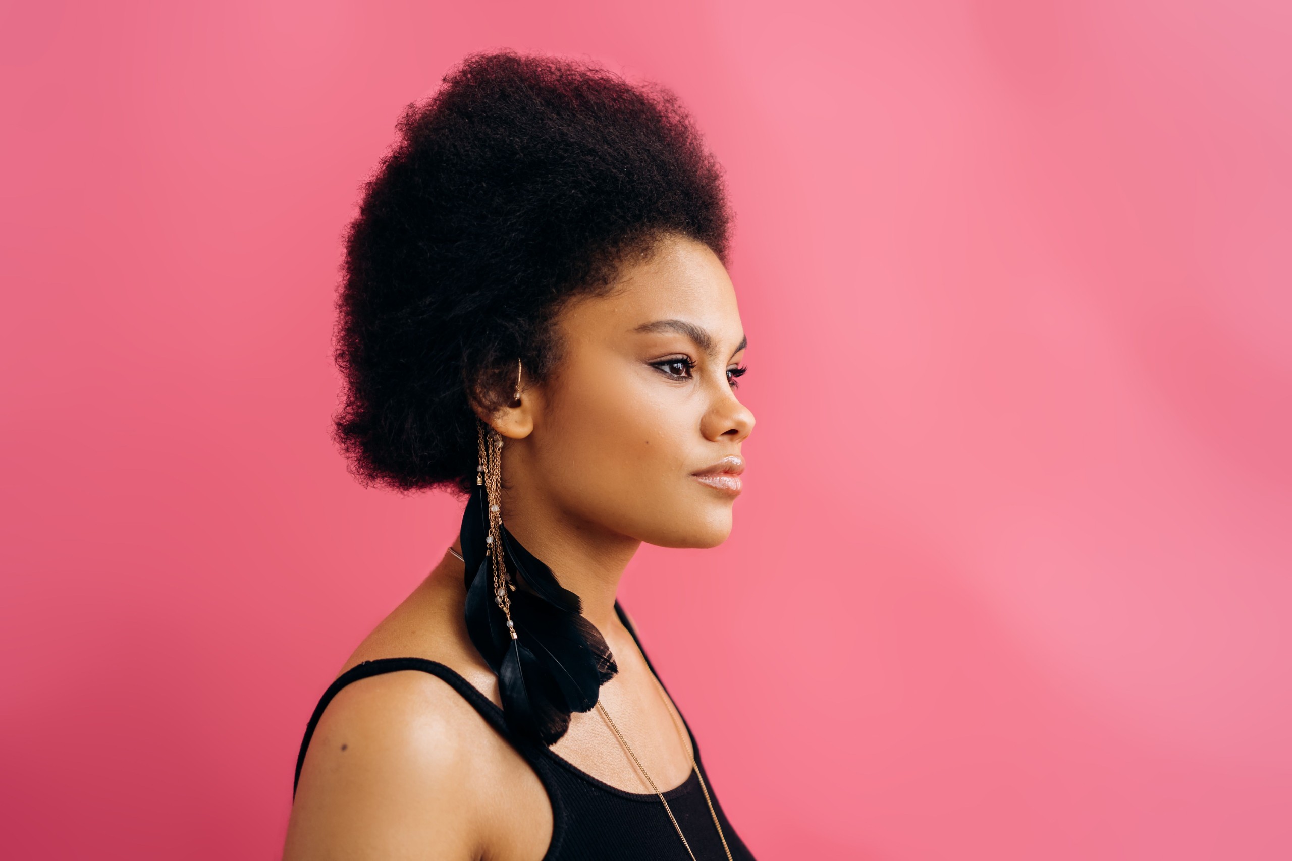 Woman with natural hair in profile on a pink background