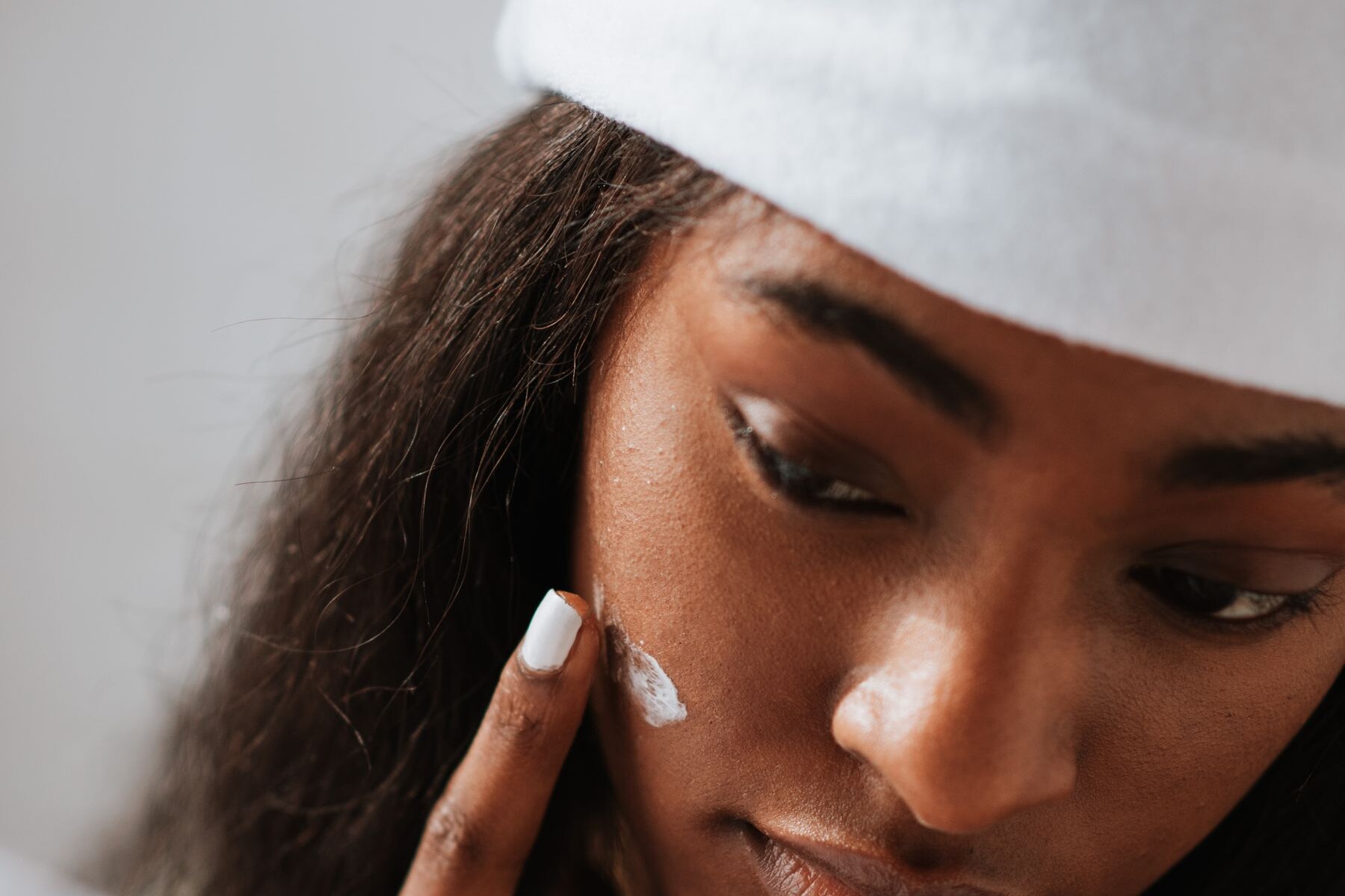 Woman with a white headband touching her face