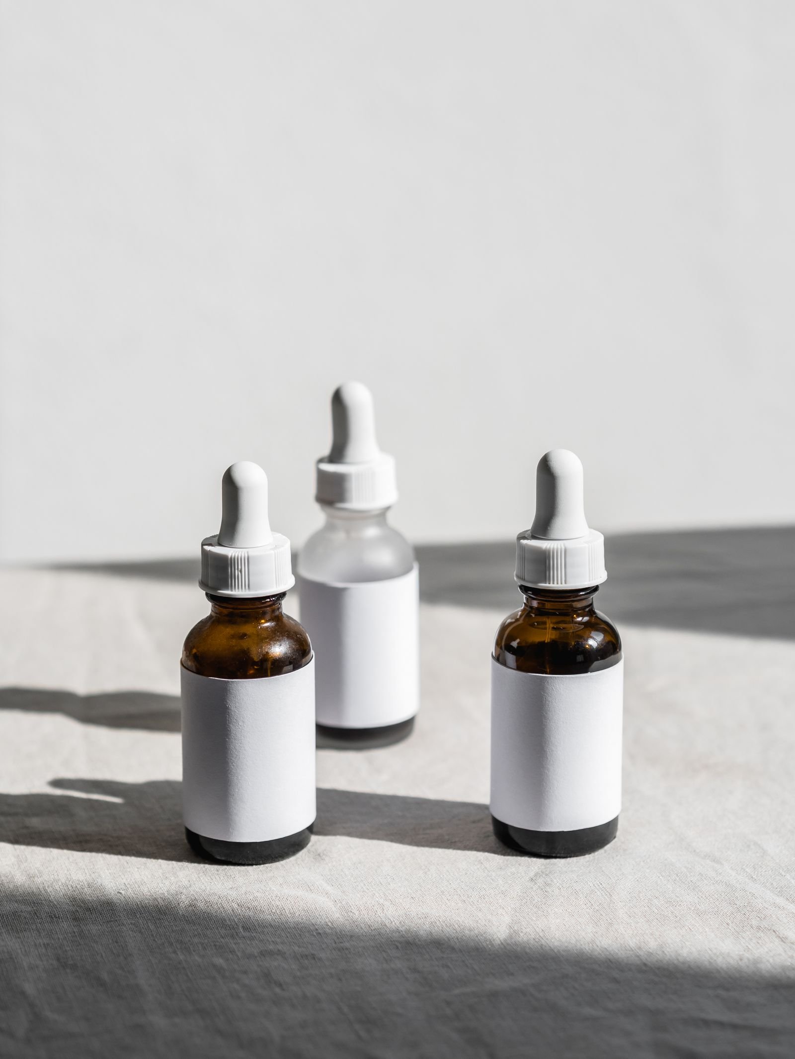 Three unlabelled dropper bottles standing on a soft neutral background