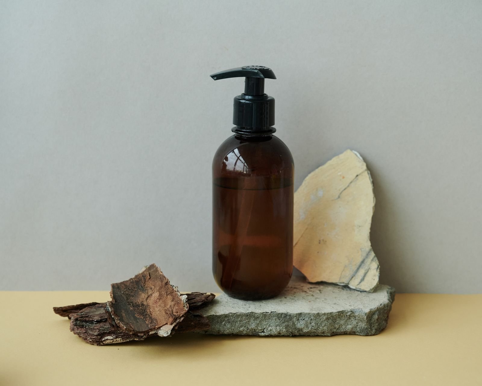 An amber pump bottle resting on stone beside a folded cloth