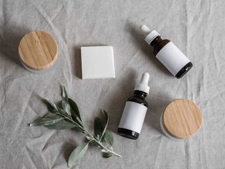Skincare bottles with wooden caps beside a sprig of greenery