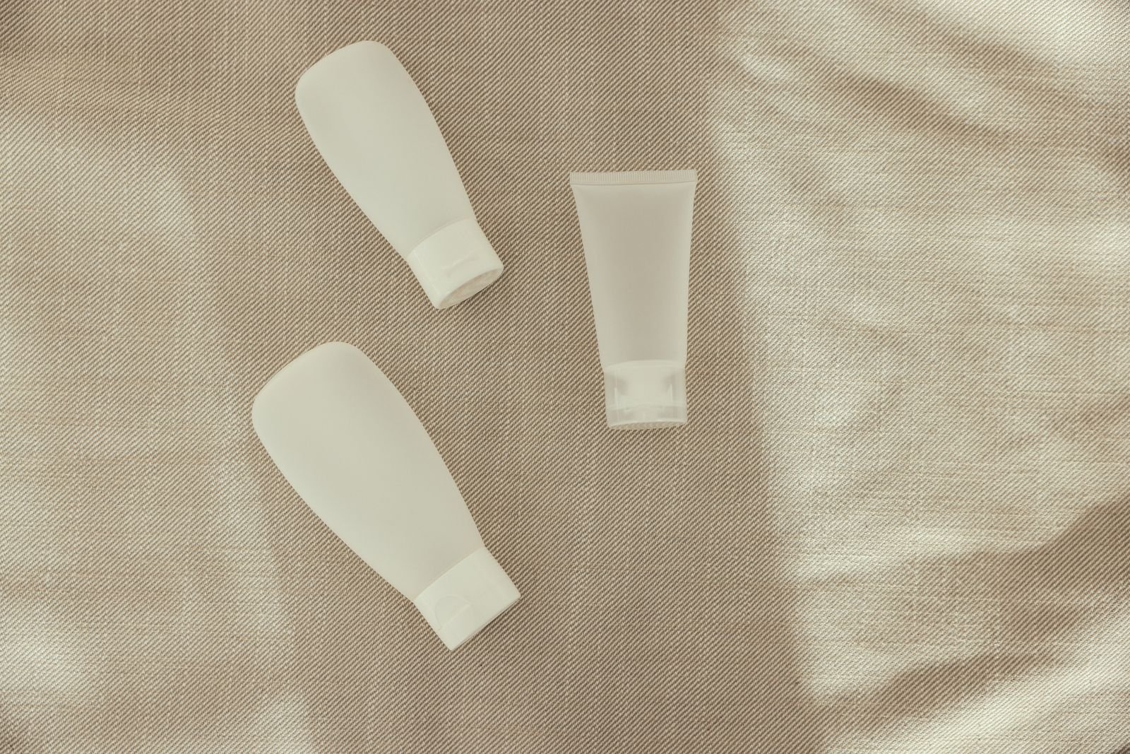 Plain unbranded squeeze bottles resting on soft neutral fabric
