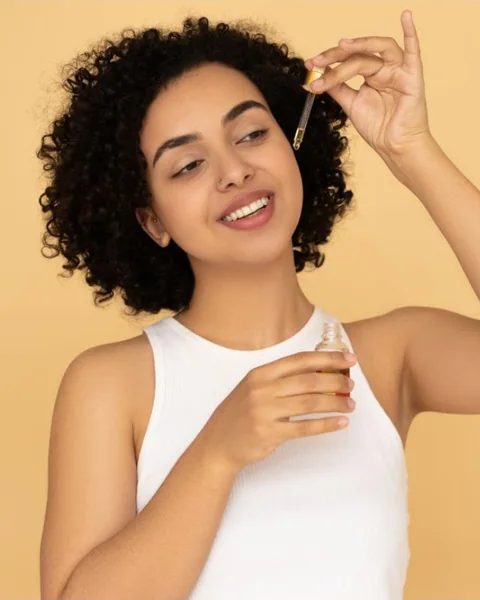 Woman with curly hair applying hair oil