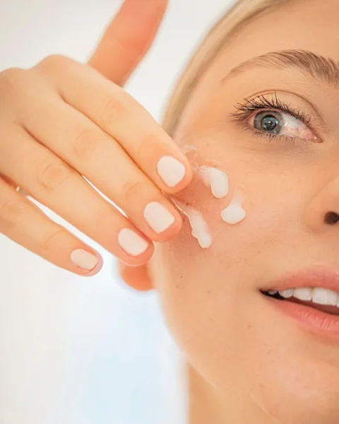 Woman applying moisturiser to her cheek