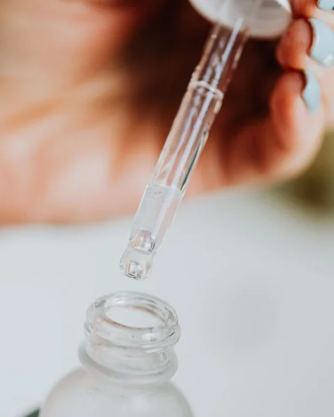 Serum dropper above a glass bottle