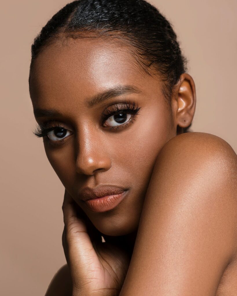 Woman with glowing skin resting her hand against her cheek